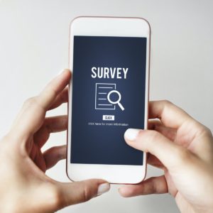 Hands holding mobile phone with depiction of a survey icon link